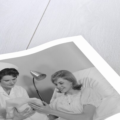 Woman nurse giving baby to smiling mother patient sitting in hospital bed by Anonymous