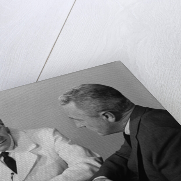Doctor sitting at desk talking to male patient by Anonymous