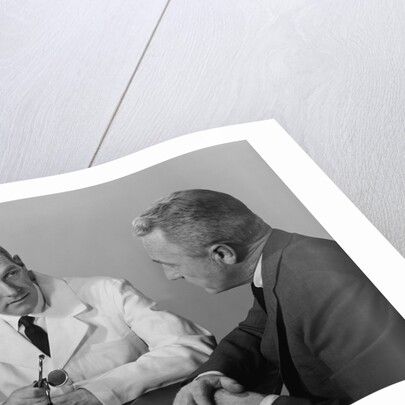 Doctor sitting at desk talking to male patient by Anonymous