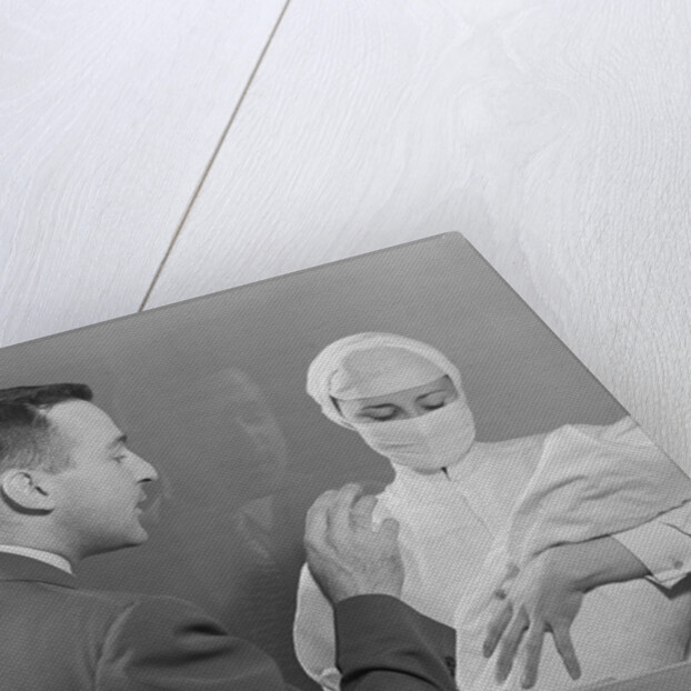 Female nurse holding infant up to father at nursery window by Anonymous