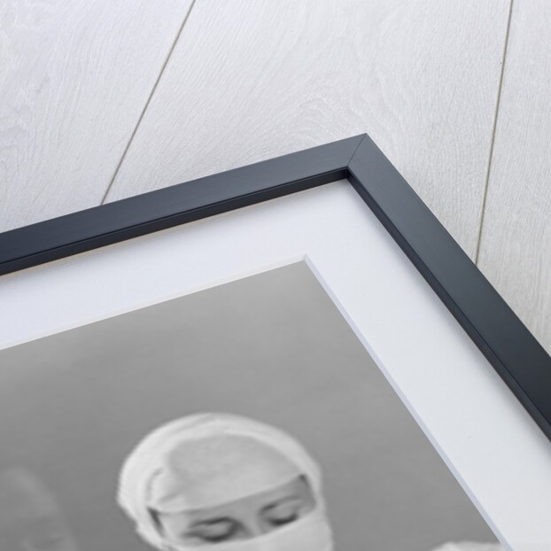 Female nurse holding infant up to father at nursery window by Anonymous