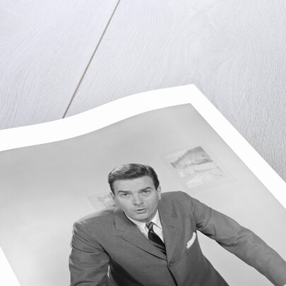 Businessman leaning over desk serious expression looking forward by Anonymous