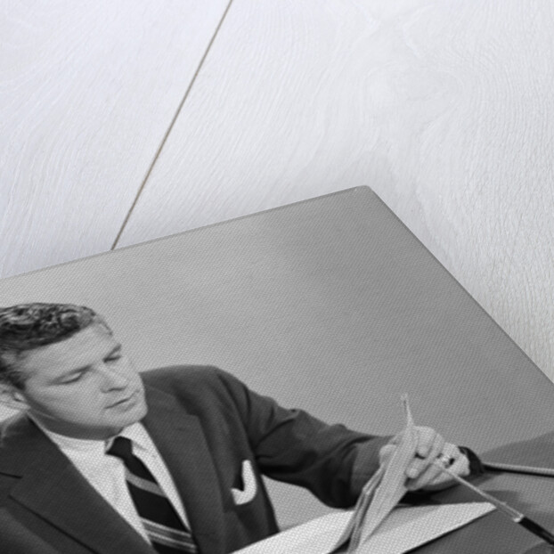 Businessman at desk looking over files papers making notes with pencil by Anonymous