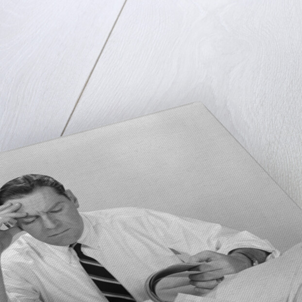 Businessman desk full papers hand to forehead serious expression by Anonymous