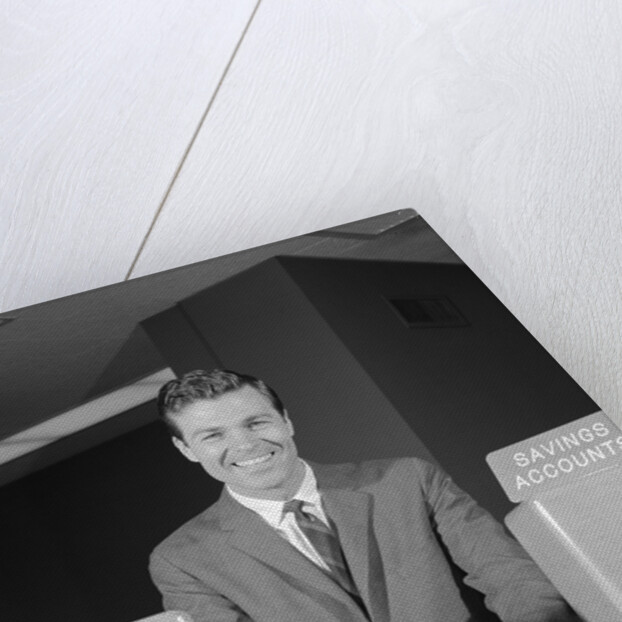 Smiling man bank teller savings accounts sign on counter by Anonymous