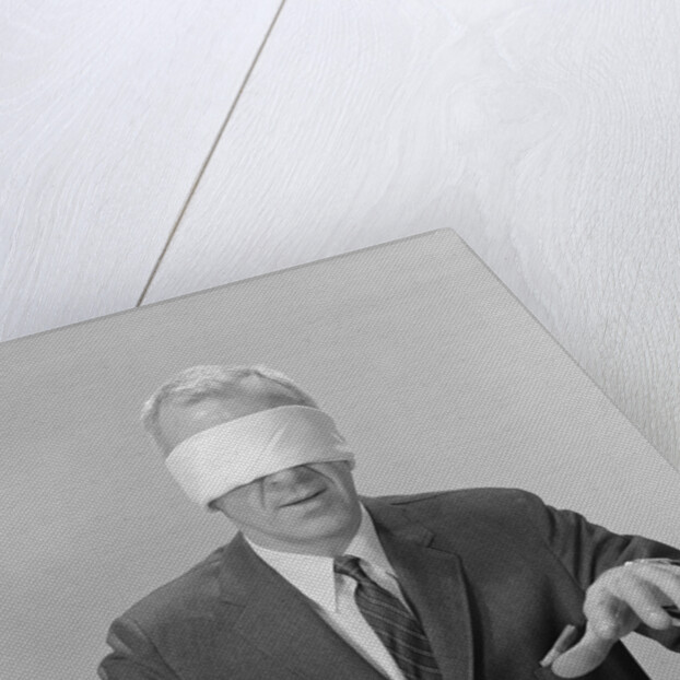 Business man hands hovering over desk wearing blindfold by Anonymous