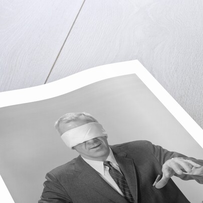 Business man hands hovering over desk wearing blindfold by Anonymous