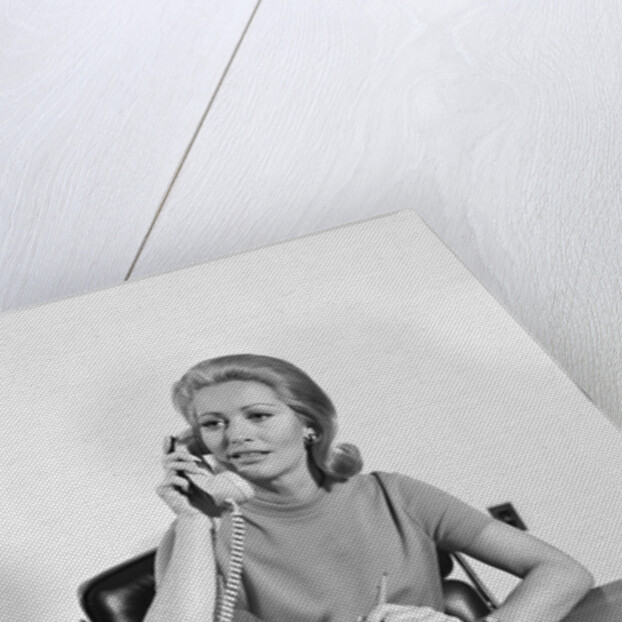 Blond businesswoman talking on telephone sitting at desk by Anonymous