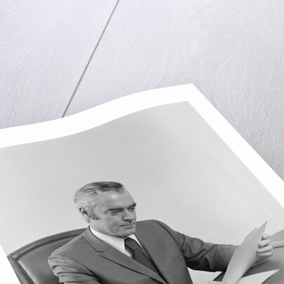 Businessman executive middle aged sitting at desk reading papers by Anonymous
