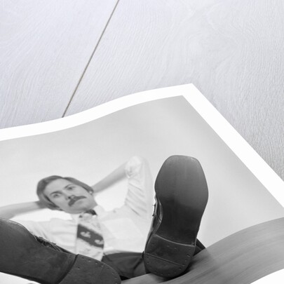 Businessman sitting feet up on desk by Anonymous