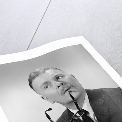 Serious thinking thoughtful older man holding eyeglasses to chin by Anonymous