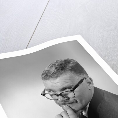 Middle aged man wearing eyeglasses low on nose quizzical facial expression by Anonymous