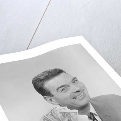 Smiling man holding a fistful of money fake bills by Anonymous