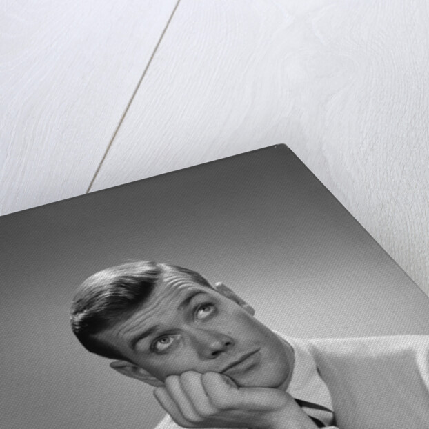 Young man hand to cheek looking up quizzical wondering thoughtful facial expression by Anonymous