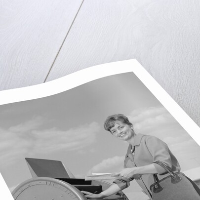 Smiling woman dropping letters in postal mail box by Anonymous