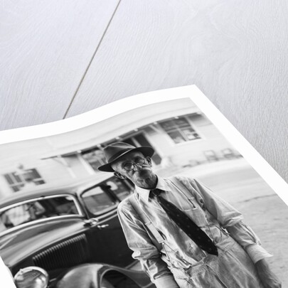 Portrait of old man wearing hat glasses tie & suspenders car in background by Anonymous