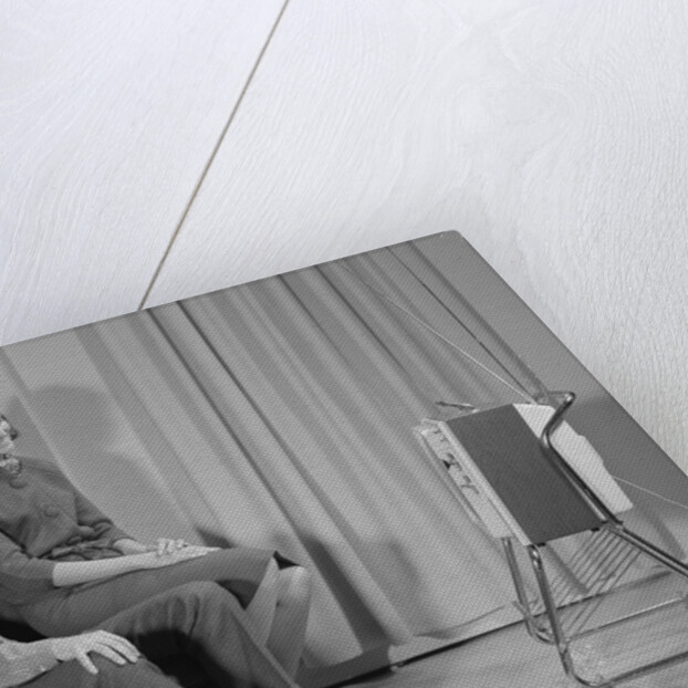 Couple man woman sitting chair watching portable television by Anonymous