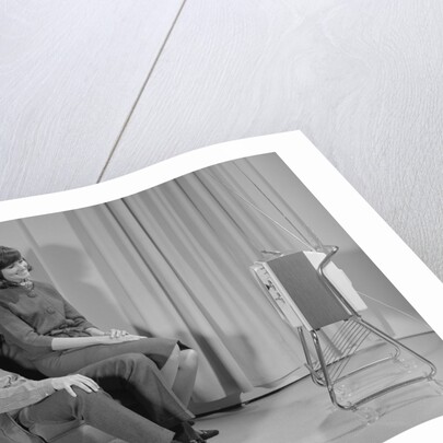 Couple man woman sitting chair watching portable television by Anonymous