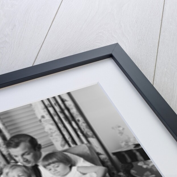 Man father sitting in chair with three children reading book by Anonymous