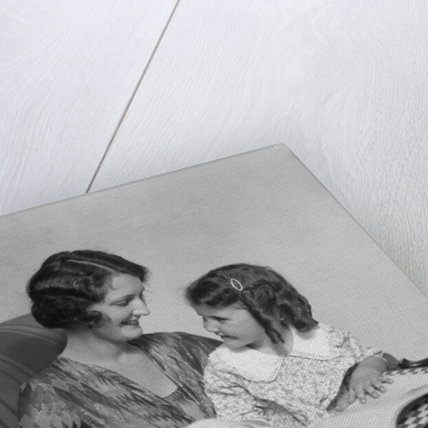 Mother & daughter smiling sitting in chair reading book by Anonymous