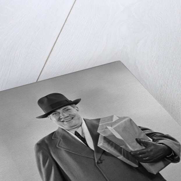 Smiling man carrying shopping boxes wearing hat coat gloves by Anonymous