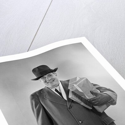 Smiling man carrying shopping boxes wearing hat coat gloves by Anonymous