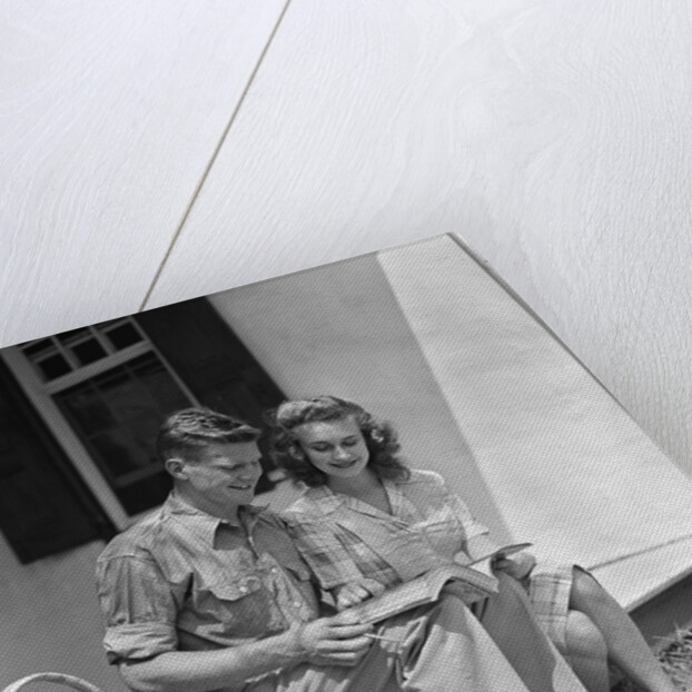 Man woman sitting on porch of farmhouse reading catalog by Anonymous