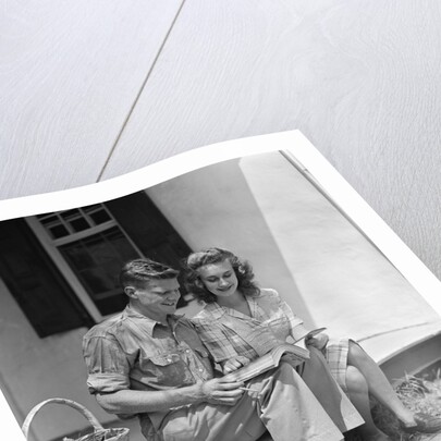 Man woman sitting on porch of farmhouse reading catalog by Anonymous