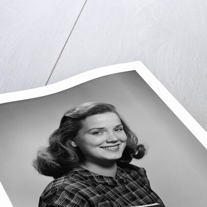 Young smiling woman holding books looking at camera by Anonymous