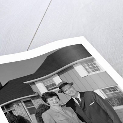 Couple smiling man and woman standing before suburban house by Anonymous