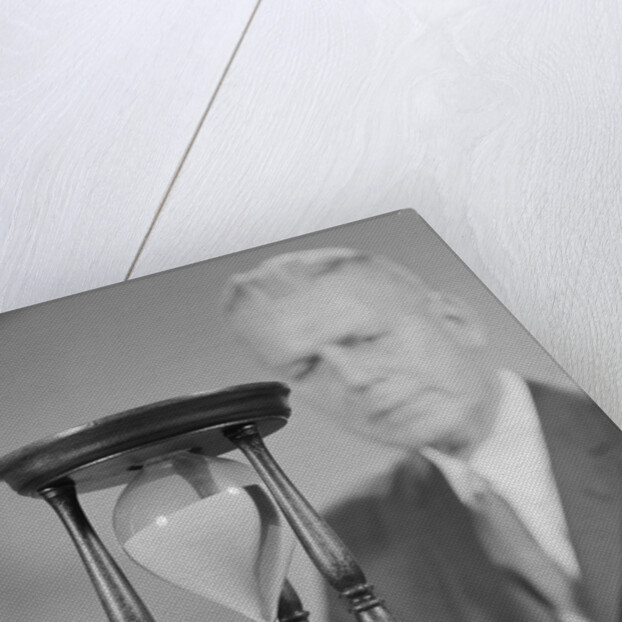 Elderly man soft focus behind hourglass by Anonymous
