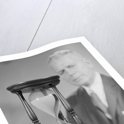 Elderly man soft focus behind hourglass by Anonymous