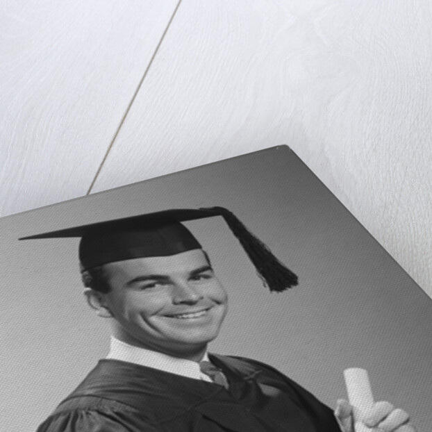 Smiling man holding diploma wearing graduation robes by Anonymous