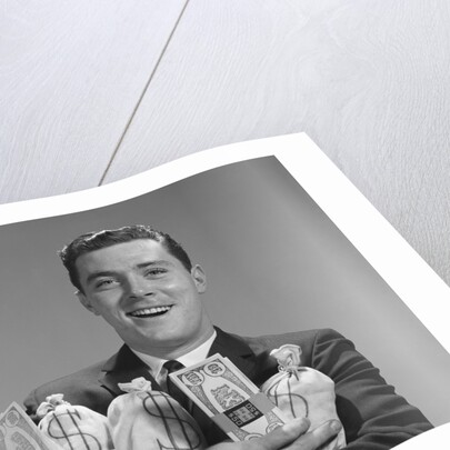 Smiling man holding money bags and bundles of cash by Anonymous