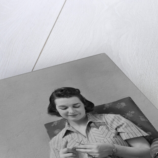 Brunette woman knitting sitting in armchair by Anonymous