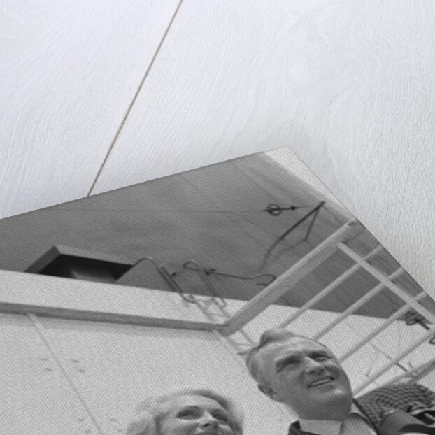 Smiling mature couple at shipboard rail with binoculars by Anonymous