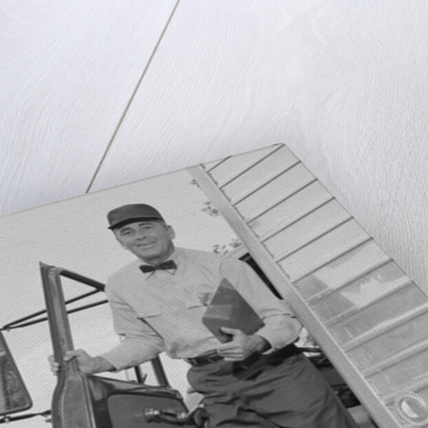 Delivery man stepping out of truck holding clipboard by Anonymous