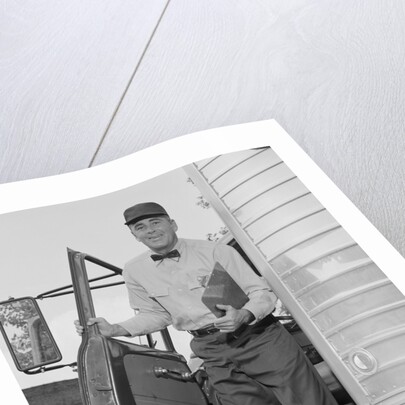 Delivery man stepping out of truck holding clipboard by Anonymous