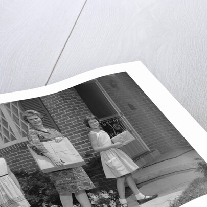 Mother and two daughters carrying shopping bags packages into house by Anonymous