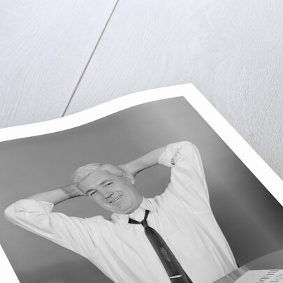 Smiling man working on family budget papers at desk by Anonymous
