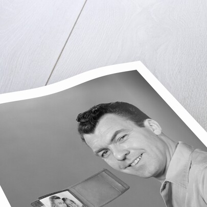 Smiling man holding up wallet with picture of wife and daughter by Anonymous