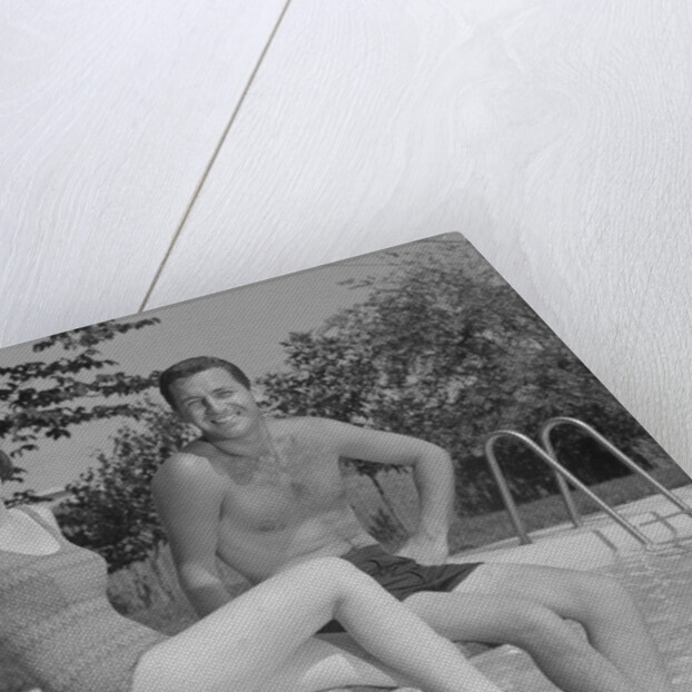 Man woman couple sitting on diving board on side of swimming pool by Anonymous