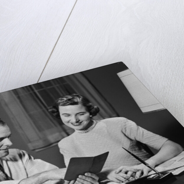 Couple man woman smiling looking at banking savings passbook at home desk by Anonymous