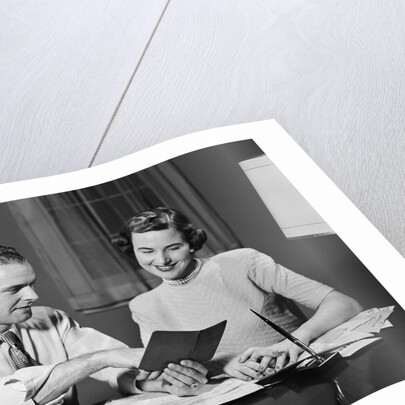 Couple man woman smiling looking at banking savings passbook at home desk by Anonymous