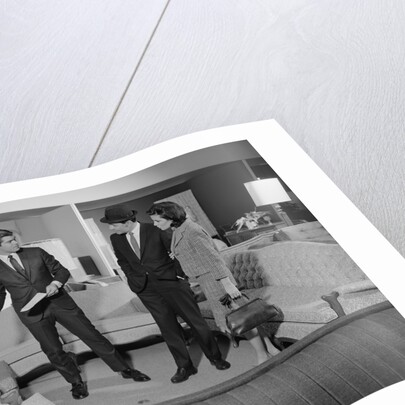 Furniture store salesman talking to couple by Anonymous