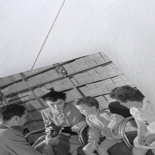 Family mother two children in shoe store trying new shoes helped by salesman by Anonymous