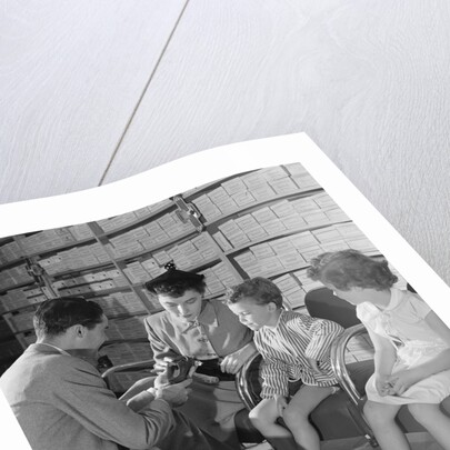 Family mother two children in shoe store trying new shoes helped by salesman by Anonymous