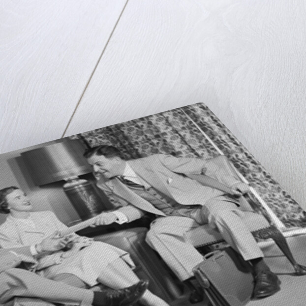 Couple sitting on couch talking to smiling insurance salesman handing them a policy by Anonymous