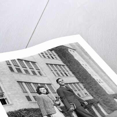 College couple walking on campus before ivy covered building by Anonymous