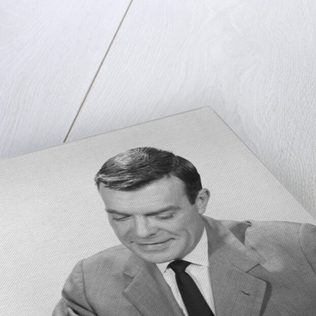 Smiling businessman at desk writing checks by Anonymous